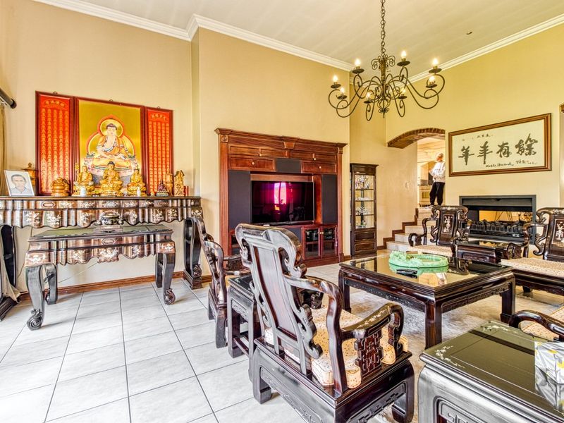Spacious living room featuring ceramic tile flooring, a built-in entertainment unit, a fireplace, and an elegant wrought iron chandelier.