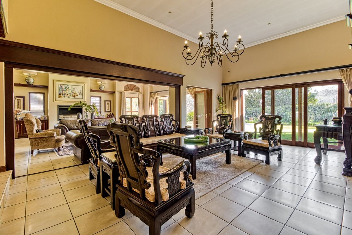 Spacious living area featuring tiled floors, a vaulted ceiling with a wrought iron chandelier, and large sliding glass doors opening to the garden.