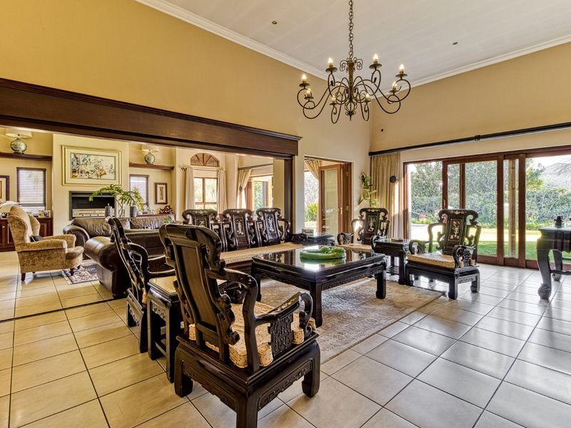 Spacious living area featuring tiled floors, a vaulted ceiling with a wrought iron chandelier, and large sliding glass doors opening to the garden.