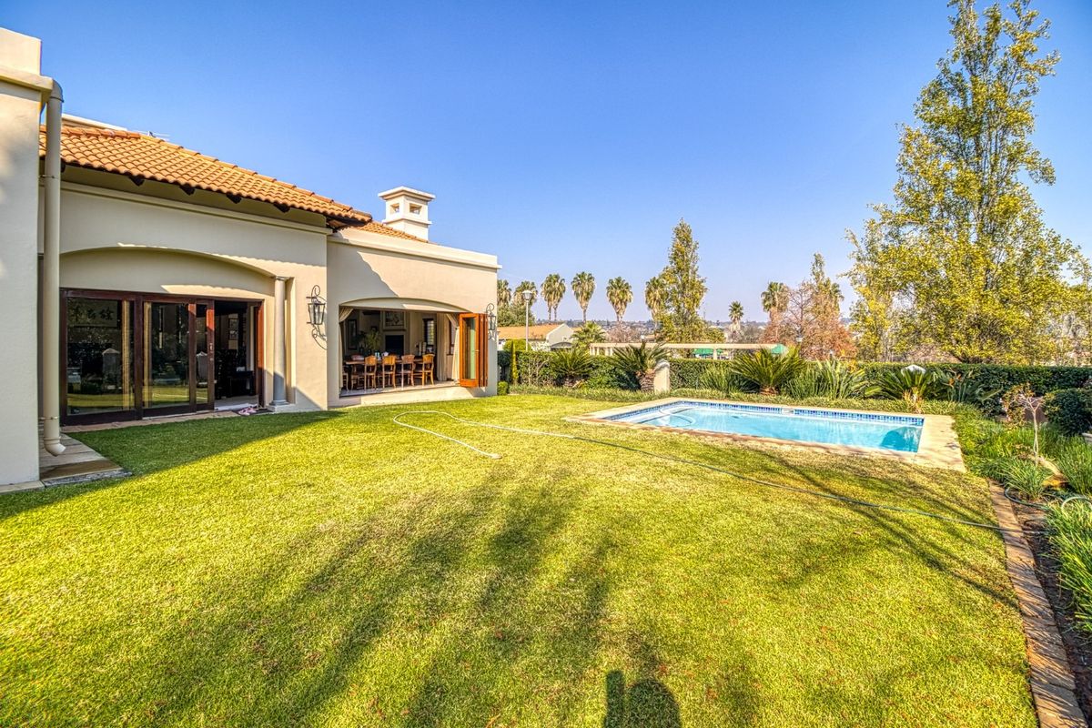 Rear view of the property featuring a well-maintained garden, a swimming pool, and a covered patio area with direct access to the interior.