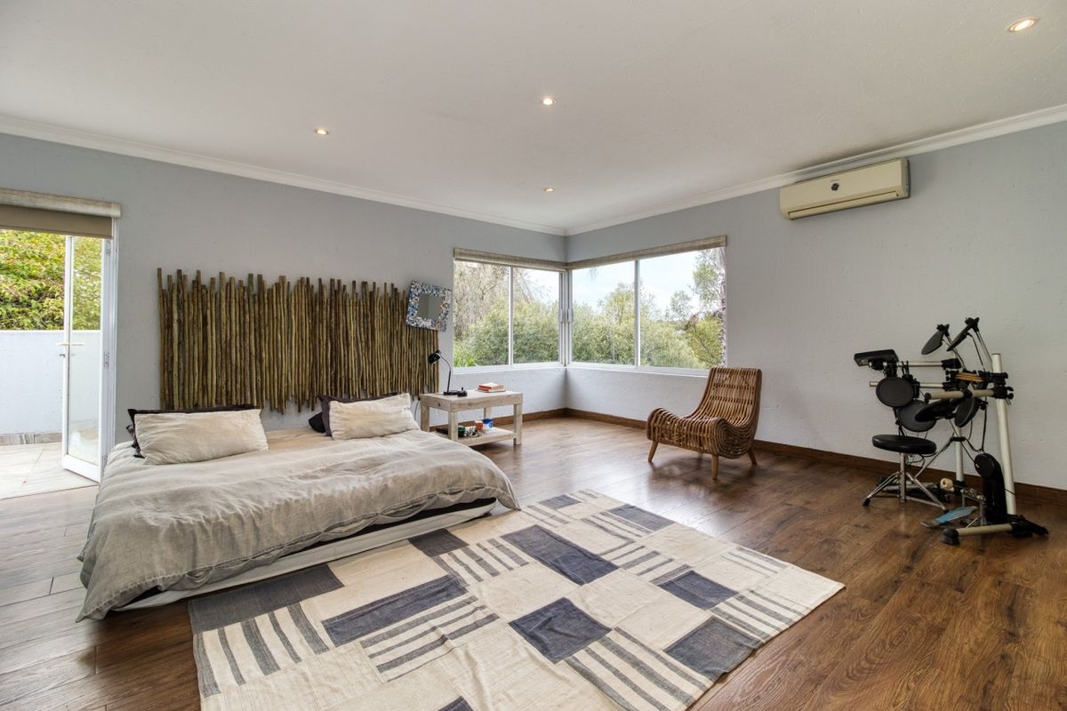Spacious bedroom featuring laminate flooring, recessed lighting, a split-system air conditioner, and large corner windows with access to an outdoor area.