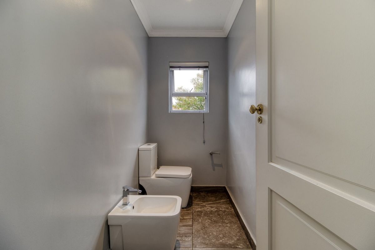 A clean and modern guest bathroom featuring a toilet, bidet, and tiled flooring with neutral wall finishes.
