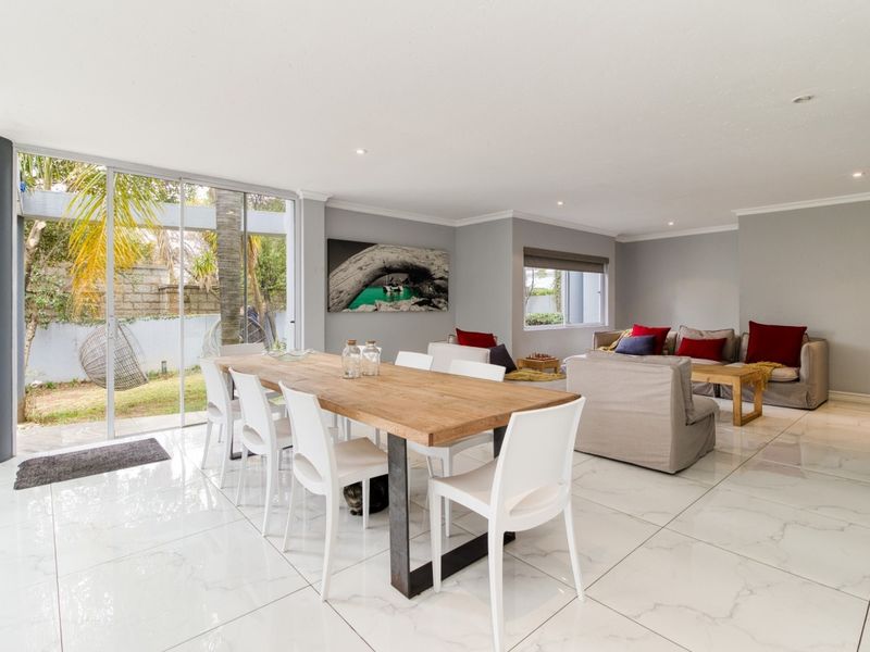 Spacious open-plan living and dining area featuring large format marble-look floor tiles and seamless access to the garden through sliding glass doors.
