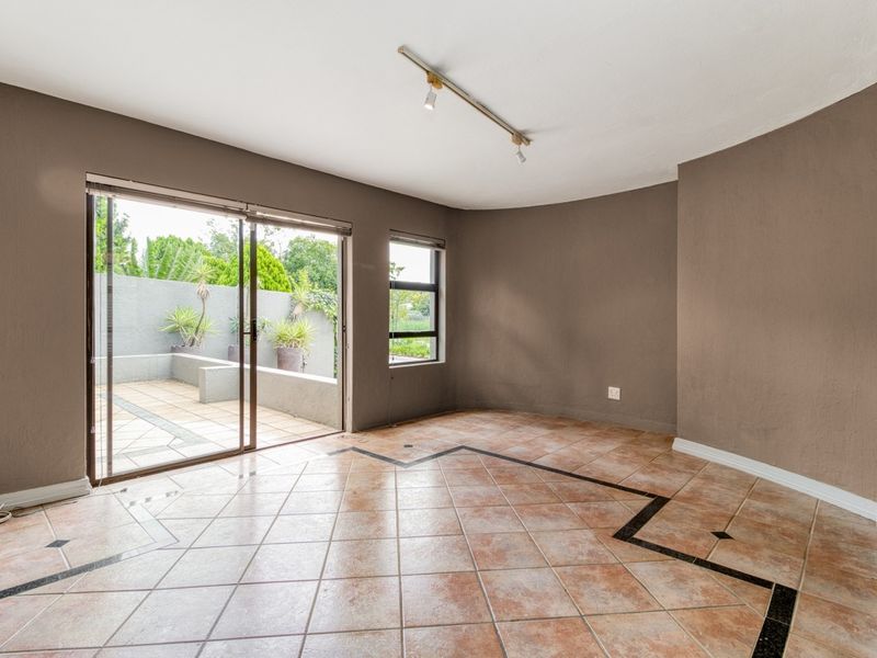 Spacious living area featuring tiled floors, track lighting, and large sliding glass doors providing direct access to the outdoor patio area.