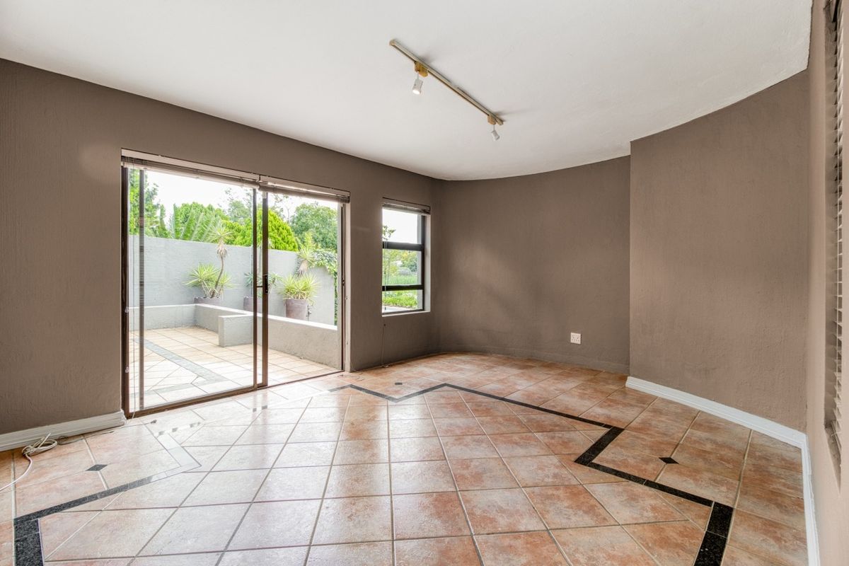 Spacious living area featuring tiled floors, track lighting, and large sliding glass doors providing direct access to the outdoor patio area.