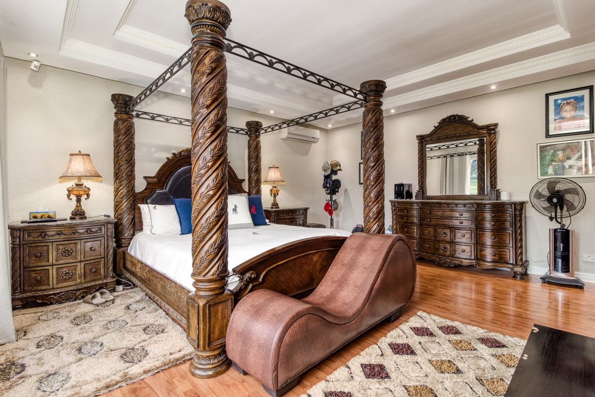 Spacious bedroom featuring decorative crown molding, recessed lighting, and wood-look flooring, complemented by a wall-mounted air conditioning unit.
