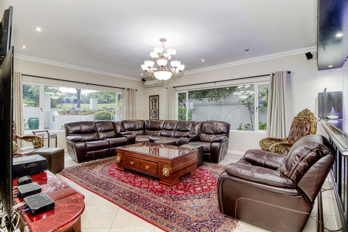 Spacious living room featuring large windows, tiled flooring, recessed lighting, and a decorative chandelier, offering a bright and comfortable atmosphere.