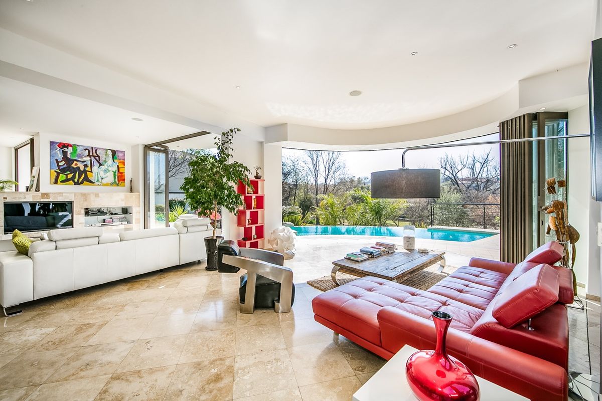 Spacious open-plan living area featuring stone tile flooring, a built-in fireplace, and large sliding doors opening to a pool deck with scenic views.