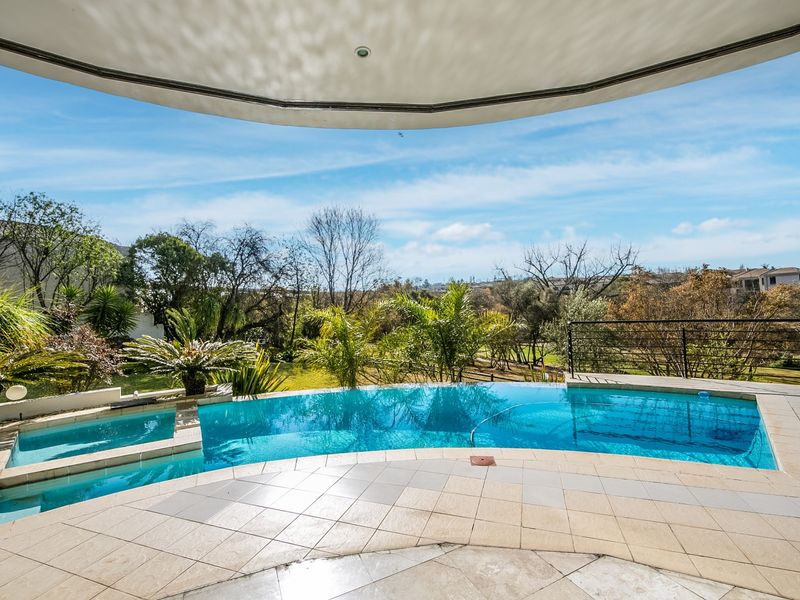 A well-maintained swimming pool area with a tiled deck, metal safety railing, and scenic views of the surrounding landscape.