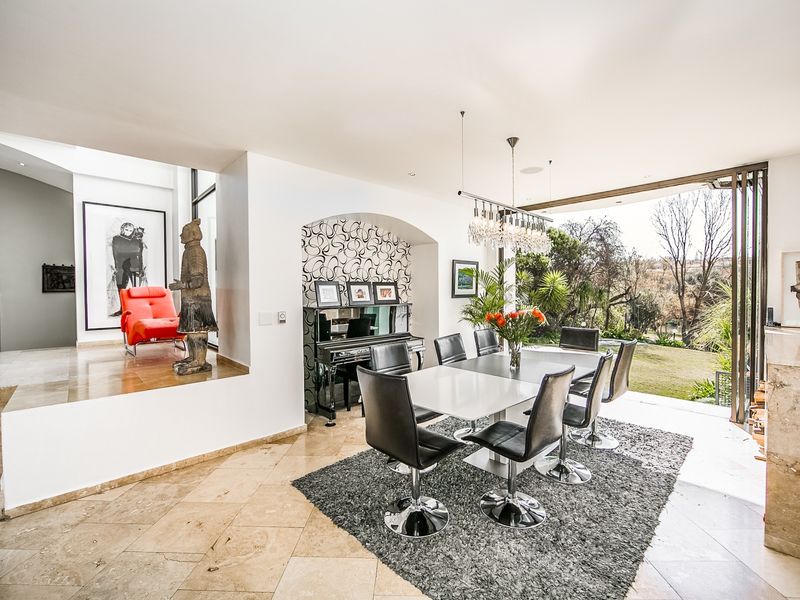 Spacious dining area featuring travertine flooring, an elegant archway, and large bi-fold doors that open to a scenic garden view.