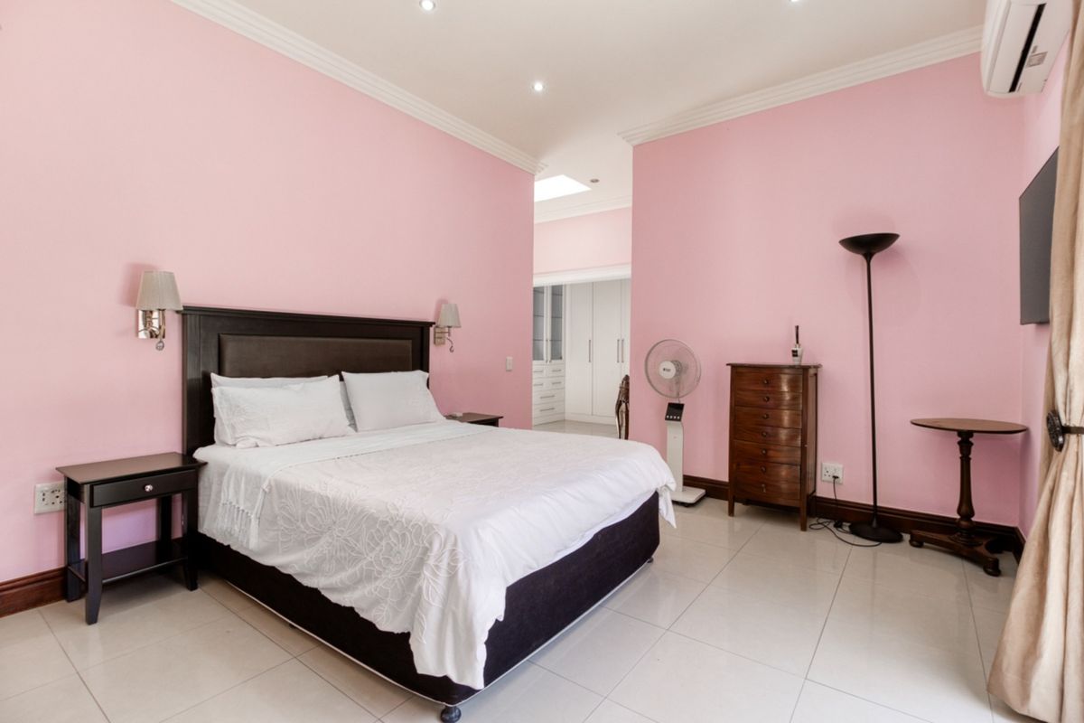 Spacious bedroom featuring tiled flooring, crown molding, recessed lighting, and a split-system air conditioner, with an adjoining walk-in closet area.