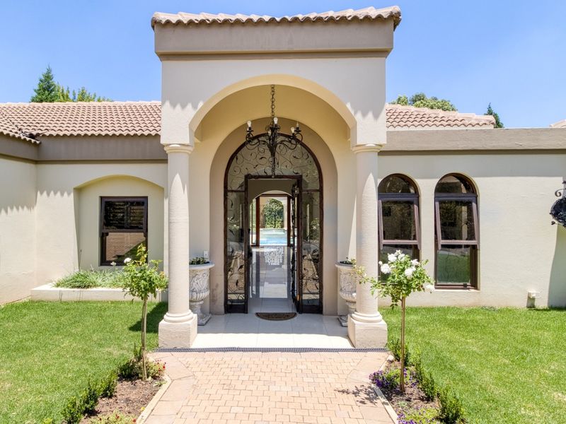 Elegant front entrance featuring an arched portico with columns, a decorative wrought iron gate, and a well-maintained paved walkway leading to the home.