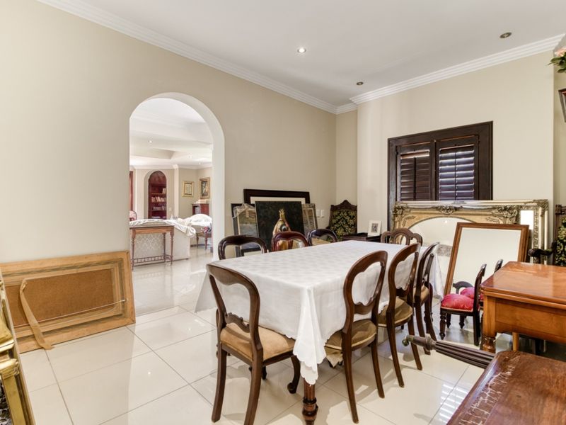A formal dining room featuring polished tile flooring, crown molding, recessed lighting, and an arched entryway leading to an adjacent living space.