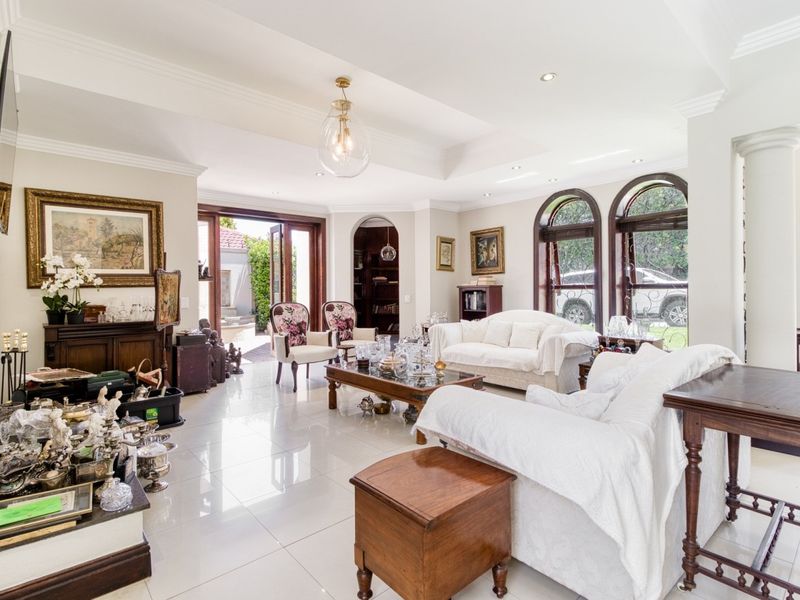 Spacious living room featuring polished tile flooring, elegant arched windows, recessed ceiling details, and direct access to an outdoor patio area.
