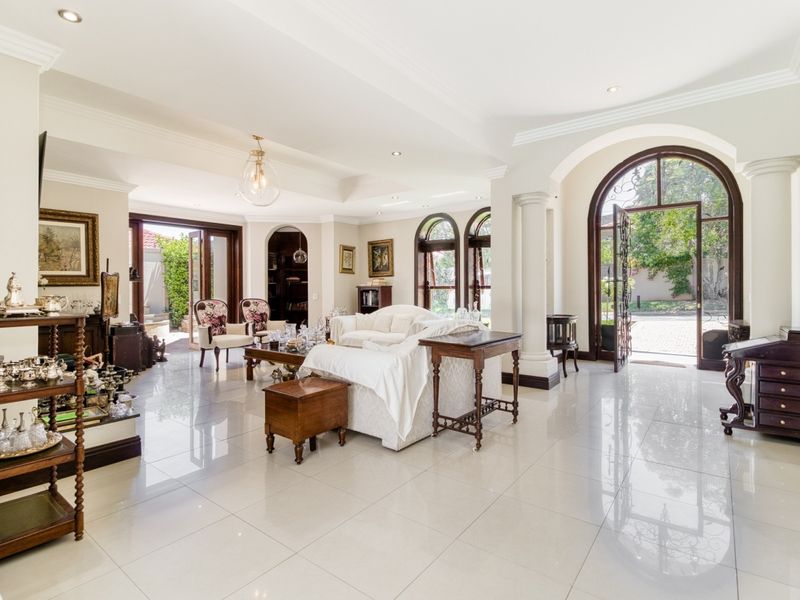 Spacious living room featuring polished tiled flooring, elegant arched doorways with decorative columns, and abundant natural light through arched windows and glass entry doors.