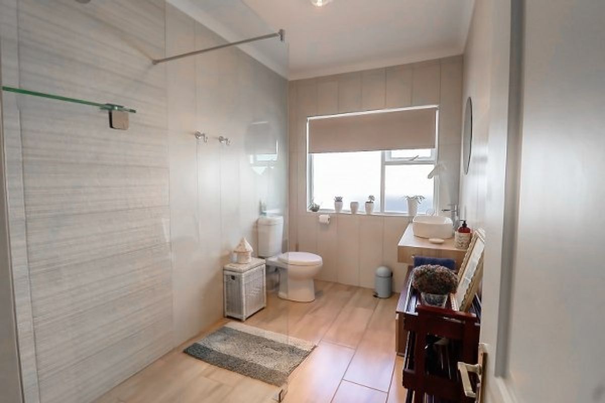 Modern bathroom featuring a walk-in shower with glass screen, floating vanity with vessel sink, and neutral tiled finishes throughout.