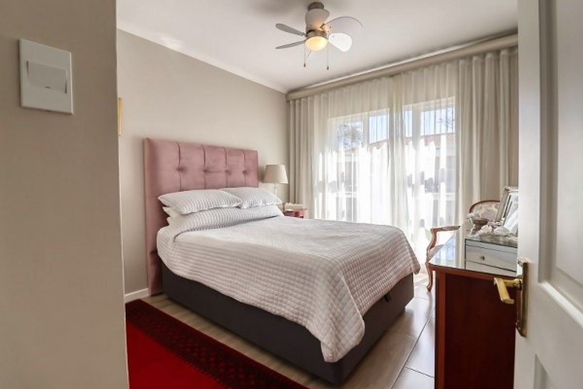 A well-maintained bedroom featuring tiled flooring, a ceiling fan, and large sliding glass doors that provide access to the exterior.