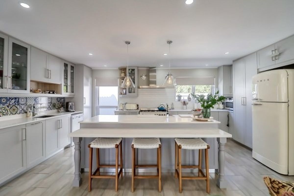 Modern, well-appointed kitchen featuring a large central island with breakfast bar, quartz countertops, custom cabinetry, and high-quality integrated appliances.