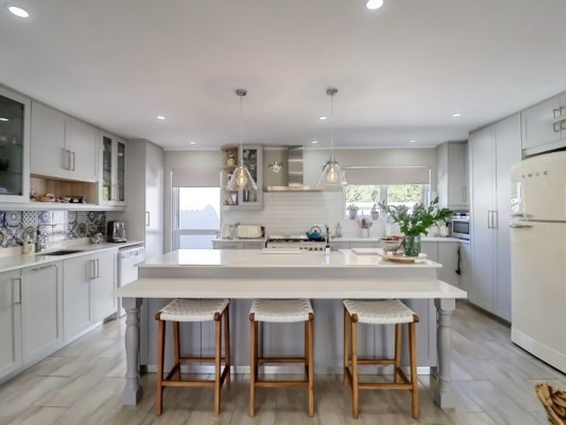 Modern, well-appointed kitchen featuring a large central island with breakfast bar, quartz countertops, custom cabinetry, and high-quality integrated appliances.