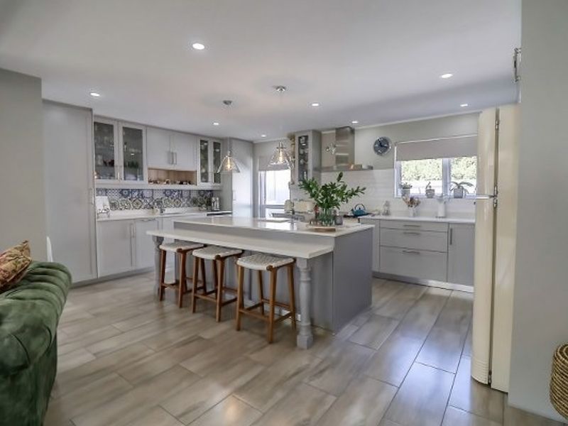 Modern kitchen featuring a central island with breakfast bar seating, sleek cabinetry, decorative backsplash, and recessed lighting throughout.