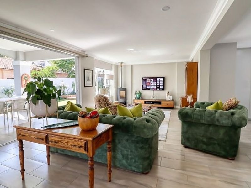 Spacious open-plan living area featuring tiled floors, a wood-burning fireplace, and large sliding doors providing seamless access to the outdoor patio.