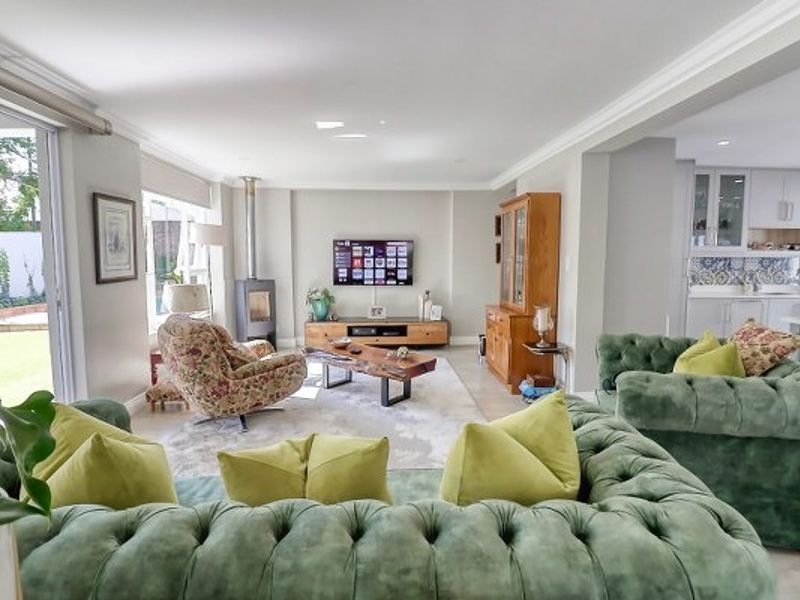 Spacious open-plan living area featuring a modern freestanding fireplace, crown molding, and seamless flow to the outdoor patio through large sliding glass doors.