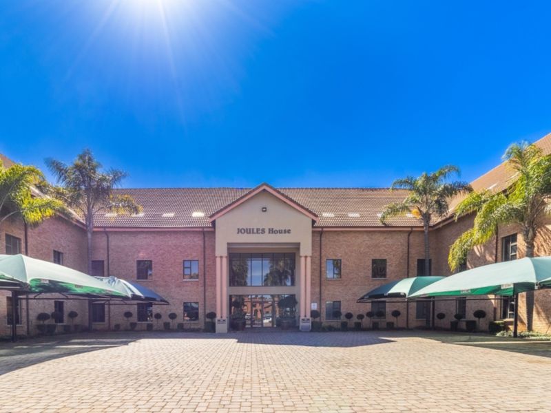 Front elevation of Joules House, featuring a brick facade, tiled roof, paved courtyard, and integrated shade cloth carports.