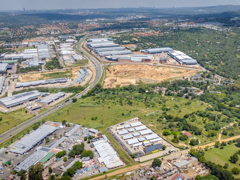 Aerial view of a commercial and industrial development area featuring multiple warehouse facilities, access roads, and surrounding undeveloped land.