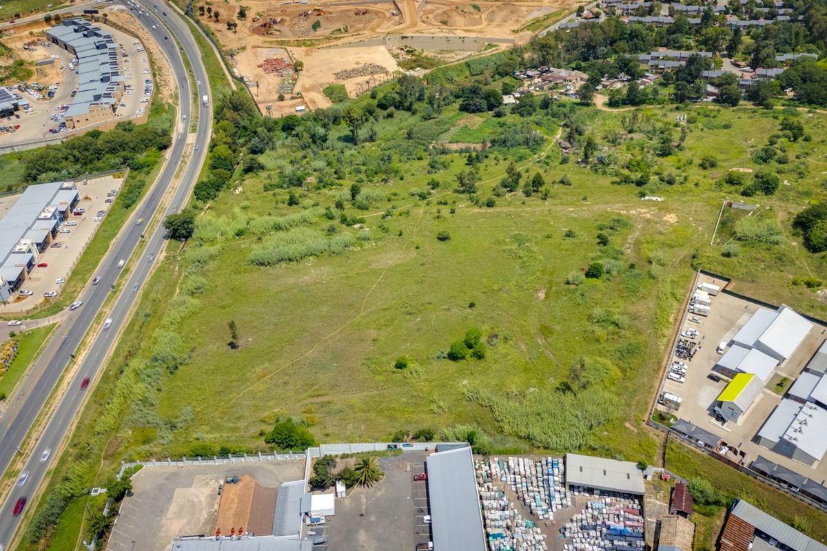 Aerial view of a vacant commercial land parcel situated near established industrial facilities and major road infrastructure.