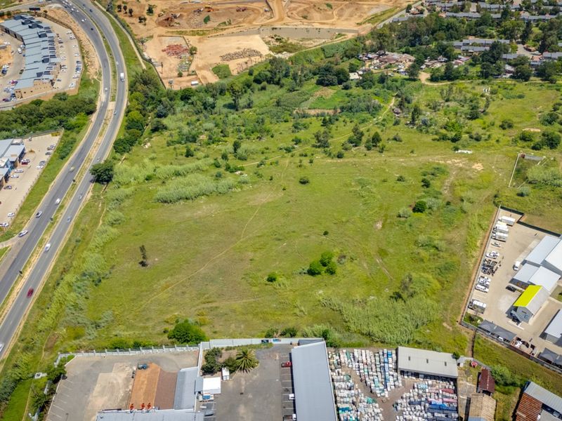 Aerial view of a vacant commercial land parcel situated near established industrial facilities and major road infrastructure.