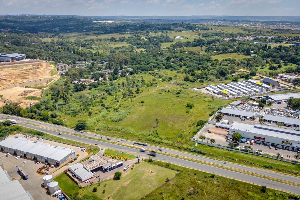 Aerial view of a large vacant commercial land parcel situated near established commercial developments and major road infrastructure.