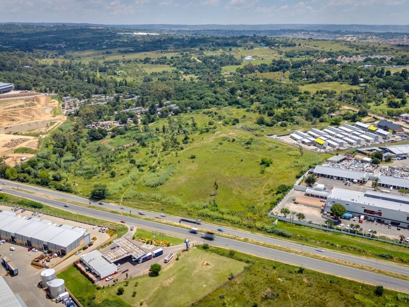 Aerial view of a large vacant commercial land parcel situated near established commercial developments and major road infrastructure.
