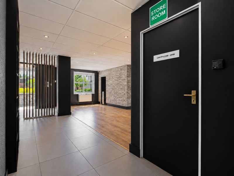 Modern office space featuring a mix of ceramic tile and timber laminate flooring, stone veneer accent wall, and contemporary black door finishes.