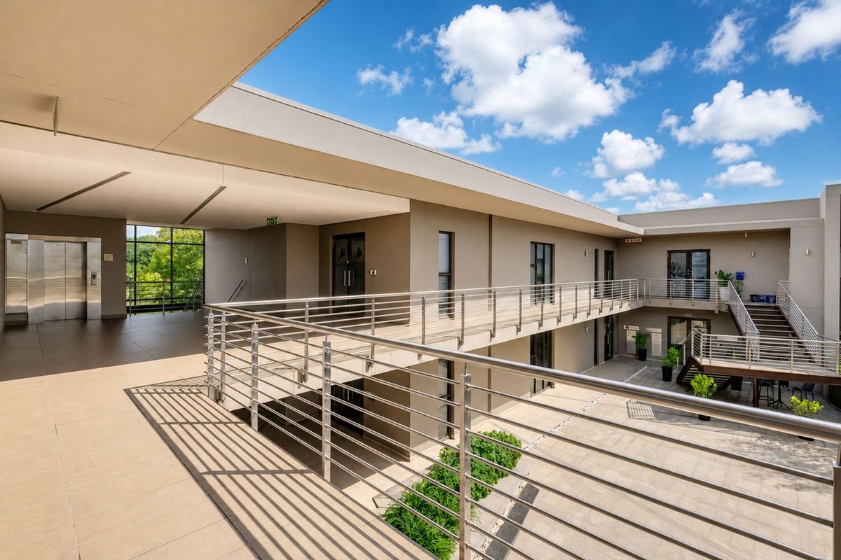 Modern office building exterior featuring a multi-level courtyard, stainless steel railings, tiled walkways, and integrated elevator access.