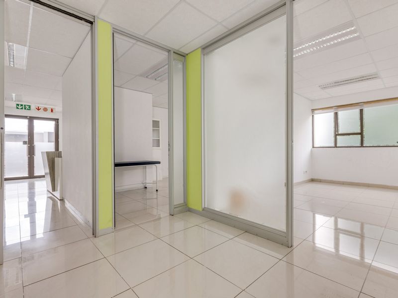 Modern office space featuring glass partitions, tiled flooring, and suspended ceilings, offering a bright and professional environment suitable for various business configurations.