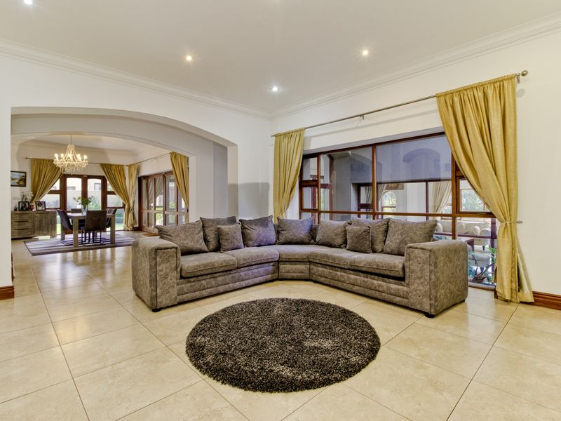 Spacious open-plan living area featuring large windows, tiled flooring, and a wide archway leading to the dining room.