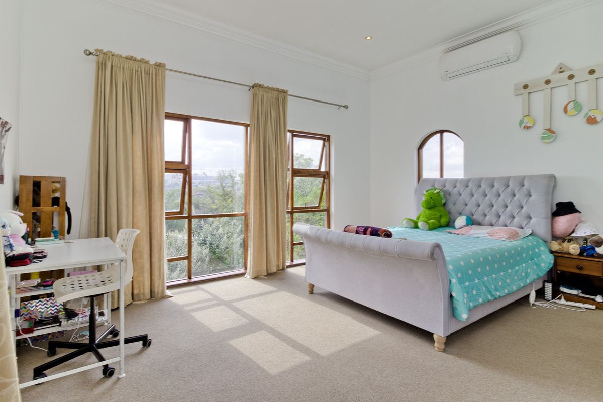 Spacious bedroom featuring carpeted flooring, split-system air conditioning, and large timber-framed windows that provide ample natural light and scenic views.