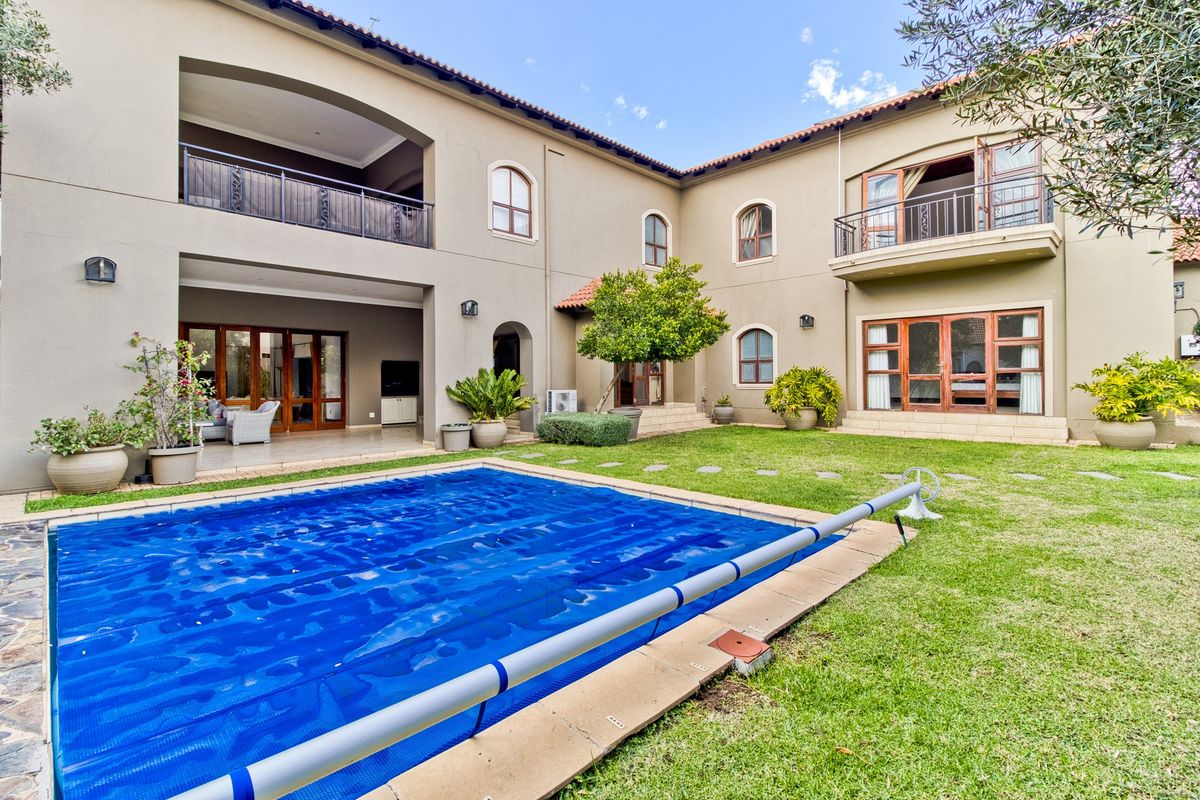 Spacious rear exterior featuring a swimming pool with cover, a covered patio area, and upper-level balconies overlooking a well-maintained garden.