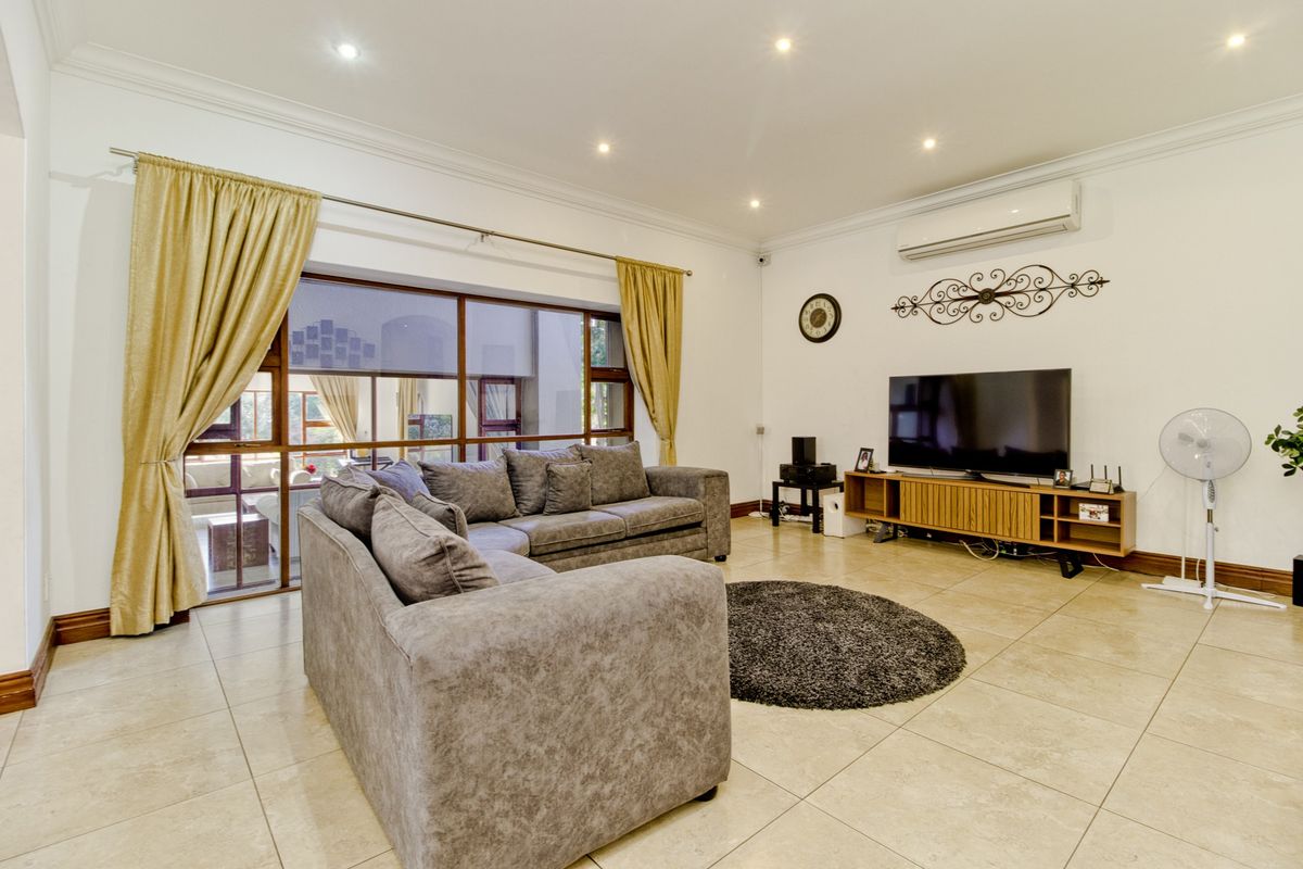 Spacious living room featuring large format floor tiles, recessed lighting, and a wall-mounted air conditioning unit with access to an outdoor area.