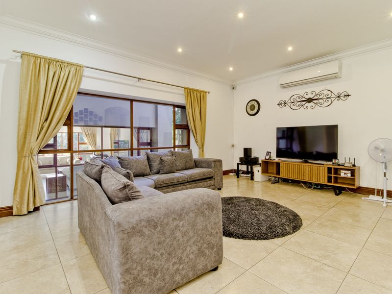Spacious living room featuring large format floor tiles, recessed lighting, and a wall-mounted air conditioning unit with access to an outdoor area.