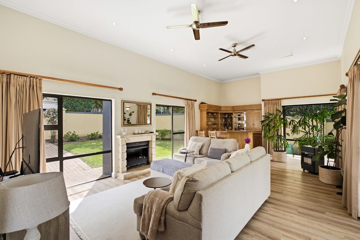 Spacious living room featuring a fireplace, built-in bar, ceiling fans, and large sliding glass doors providing direct access to the garden.