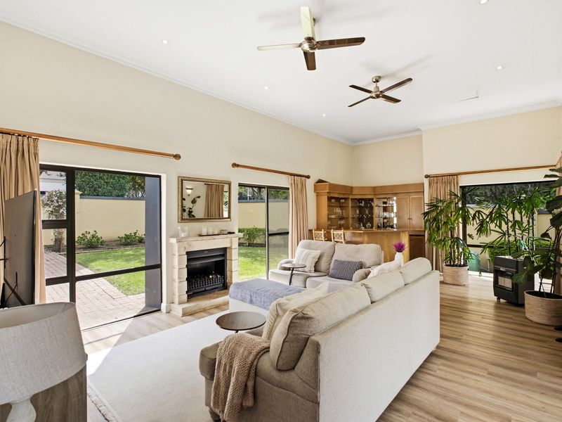 Spacious living room featuring a fireplace, built-in bar, ceiling fans, and large sliding glass doors providing direct access to the garden.