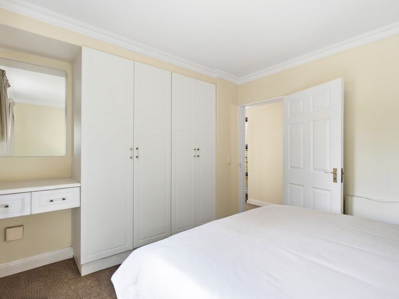 A well-maintained bedroom featuring built-in cupboards, a matching vanity unit, crown molding, and neutral wall finishes.