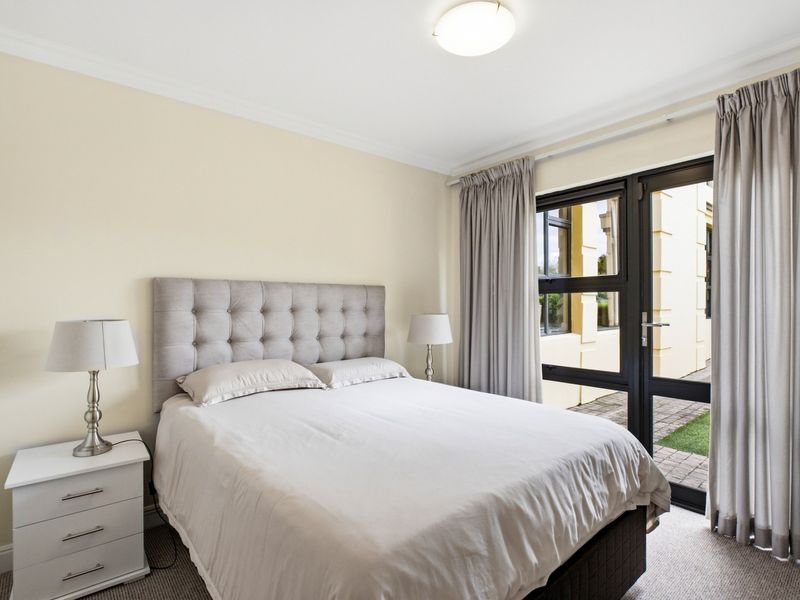 A well-maintained bedroom featuring neutral walls, carpeted flooring, and direct access to an outdoor area through glass-paned french doors.