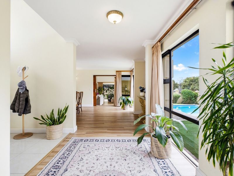 Spacious open-plan living area featuring hardwood flooring, large sliding glass doors providing pool views, and elegant ceiling cornicing.