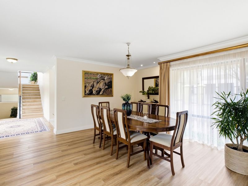 A bright and spacious dining area featuring modern laminate flooring, elegant pendant lighting, and large sliding glass doors that provide access to the outdoors.
