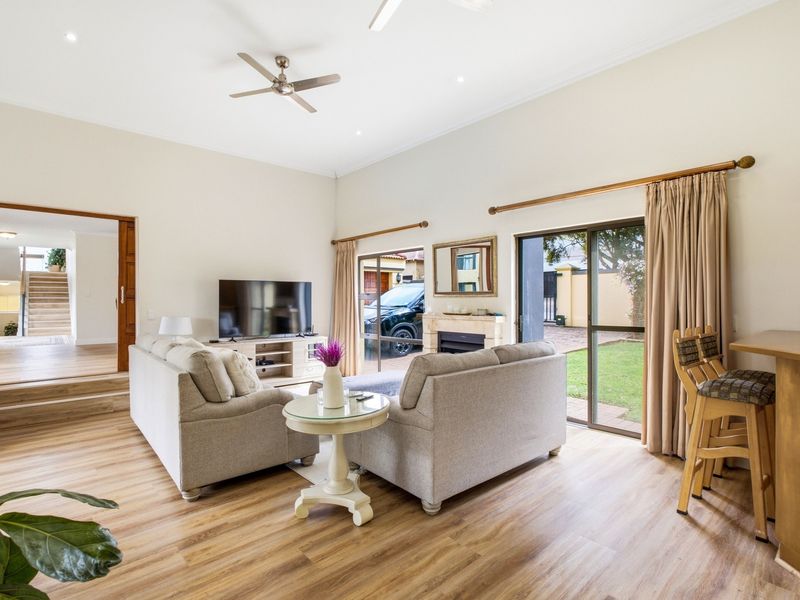Spacious living room featuring high ceilings, laminate flooring, a built-in fireplace, and sliding glass doors providing direct access to the garden area.