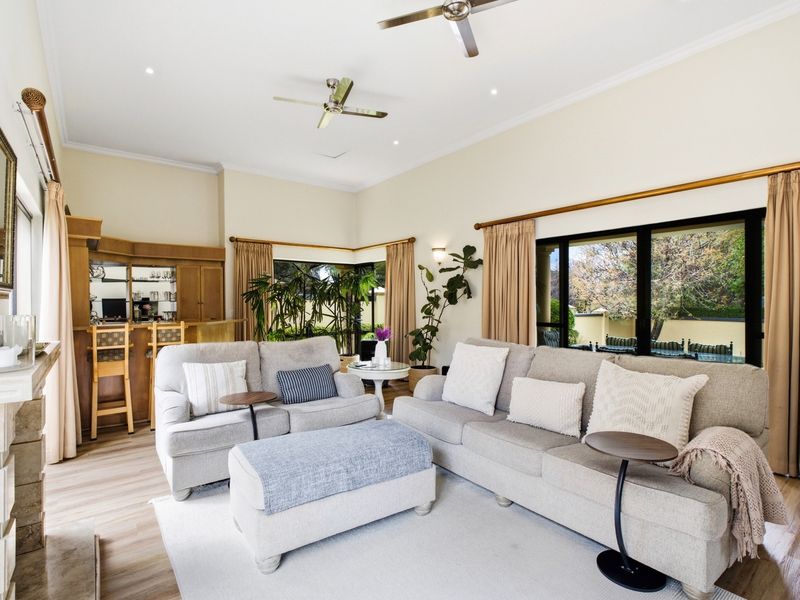 Spacious living room featuring a built-in bar, stone fireplace, ceiling fans, and large sliding glass doors providing access to the outdoor area.