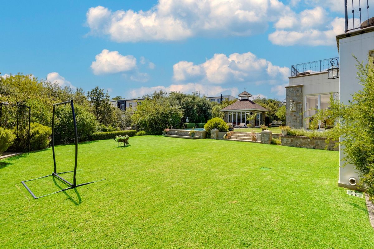 Spacious rear garden featuring a well-maintained lawn, stone retaining walls, a swimming pool, and a detached gazebo structure.