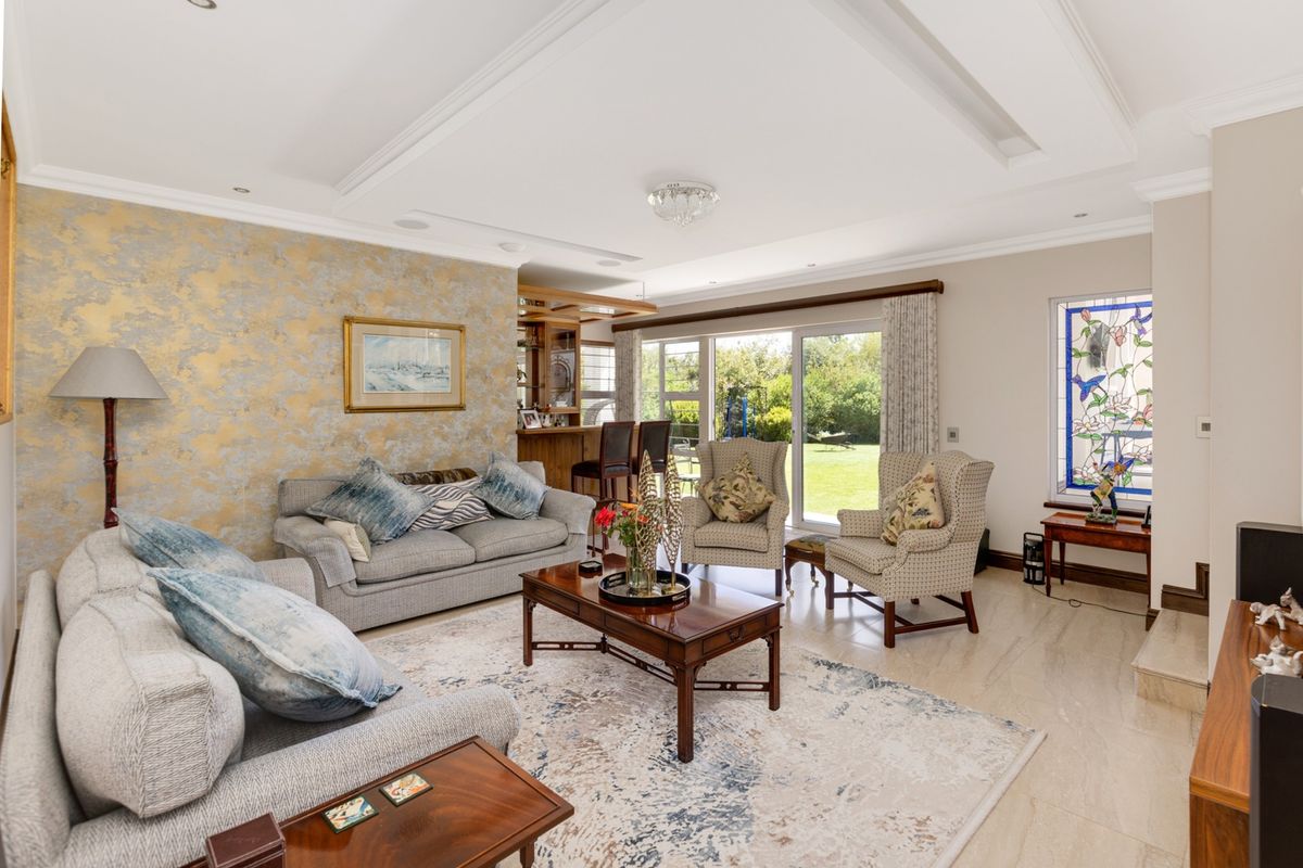 Spacious living room featuring a built-in bar, recessed ceiling detail, tiled flooring, and large sliding doors opening to the rear garden.